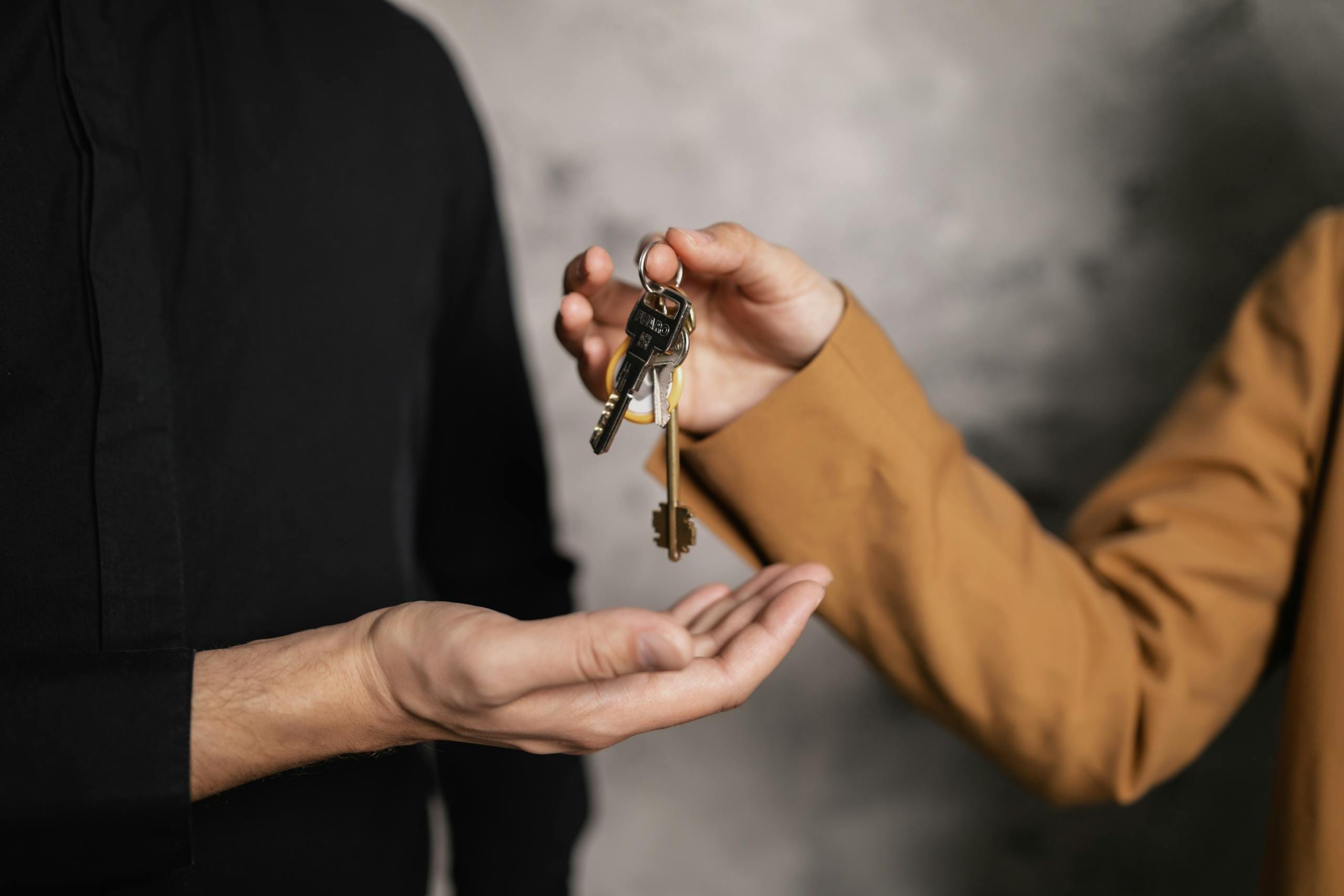 Close-up of one person handing over keys to another